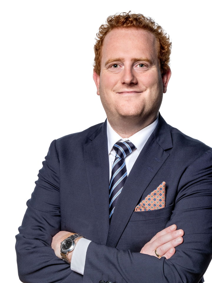 Portrettbilde av en mann med dress, slips og tørkle i dressjakkelomma. Foto